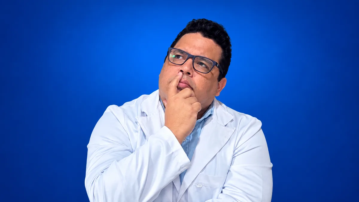 Professor Thiago Santos pensativo, com a mão no queixo, em fundo azul